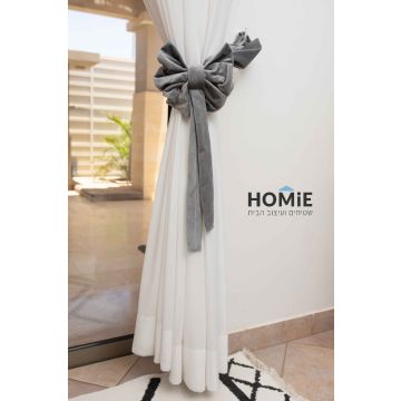 חבק פפיון דקורטיבי קטיפה לוילון בצבע אפור. החבק המהודר והיוקרתי המגיע בסגנון הרטרו כפרי ישדרג את מראה הוילון שלכם בכמה רמות ויאסוף אותו בצורה אפקטיבית ונעימה לעין. הוא מיוצר בעבודת יד על ידי אמן מוכשר שהשקיע בו עבודה מרובה. החבק יתאים לסלון, חדר שינה, חדר