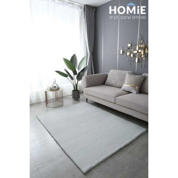 שטיח פרווה אוף וויט דגם פיור מונח ונראה בשלמותו בסלון על הרצפה, למרגלות הספה, מוסיף חמימות