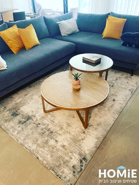 שטיח אבסטרקטי מודרני בצבעי שמנת, אפור וכחול מונח בסלון